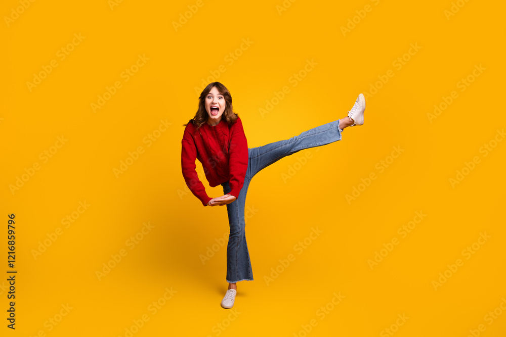 Obraz premium Happy young woman posing energetically in a bright red sweater against a vibrant yellow background