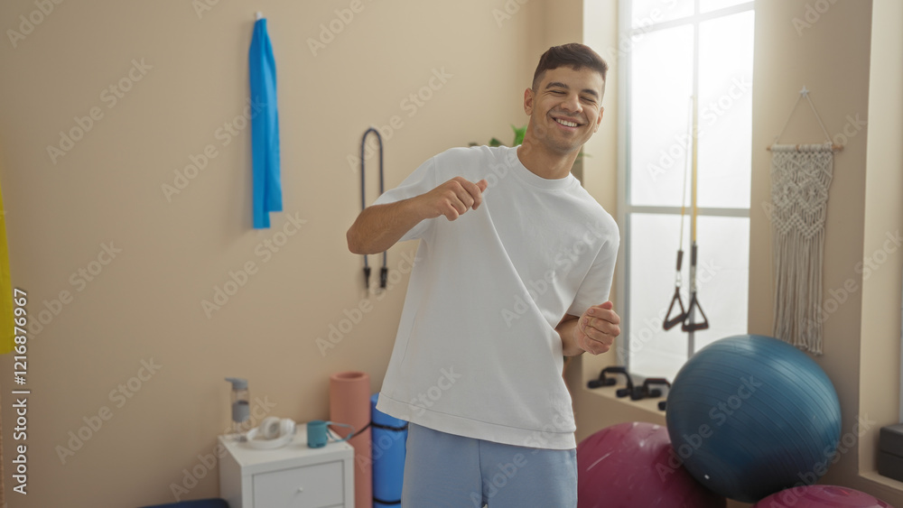 Obraz premium Young man smiling in gym environment with exercise equipment and bright interior showcasing active lifestyle and fitness motivation.