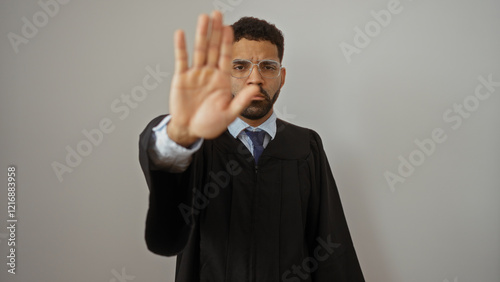 Serious man with glasses and a beard wearing a black robe and tie making a stop gesture with his hand against a white background