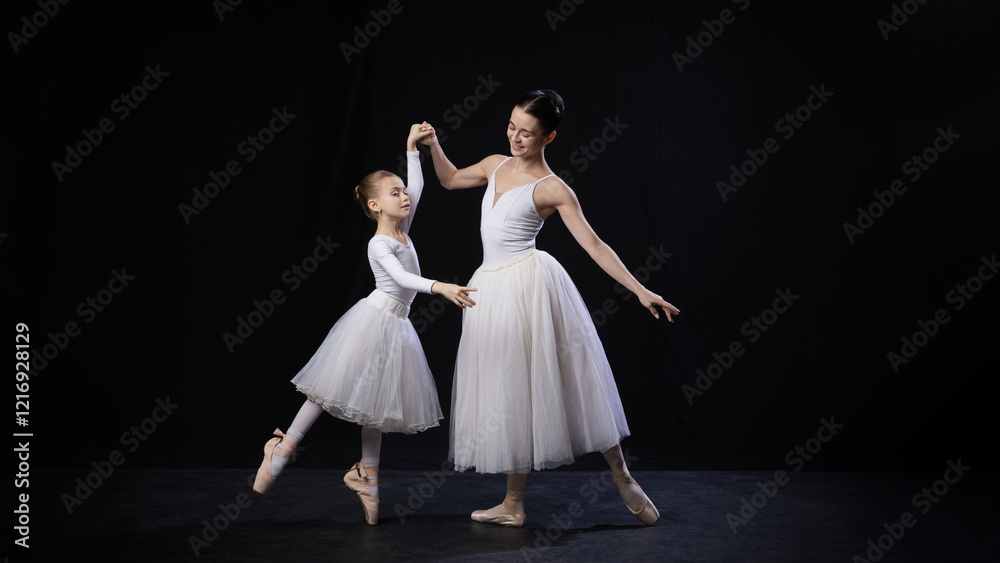 Adult ballerina assisting child in dance position, both smiling gently while holding hands, dressed in white ballet costumes, against black background. Concept of ballet, elegance and beauty, grace. Adult ballerina assisting child in dance position, both smiling gently while holding hands, dressed in white ballet costumes, against black background. Concept of ballet, elegance and beauty, grace.