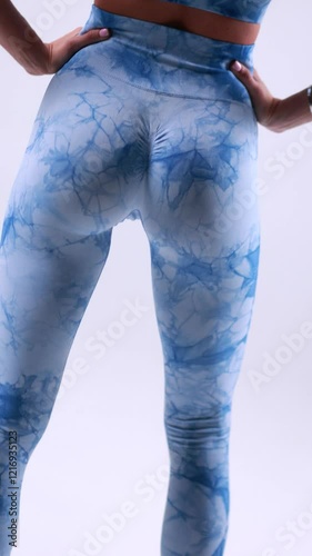 Fit woman in blue marble activewear with hands on hips showcasing healthy lifestyle activewear concept