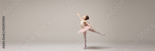 Banner. Little ballerina posing in arabesque position with arms forming graceful move against white studio background with negative space. Concept of ballet, elegance and beauty, grace. Ad