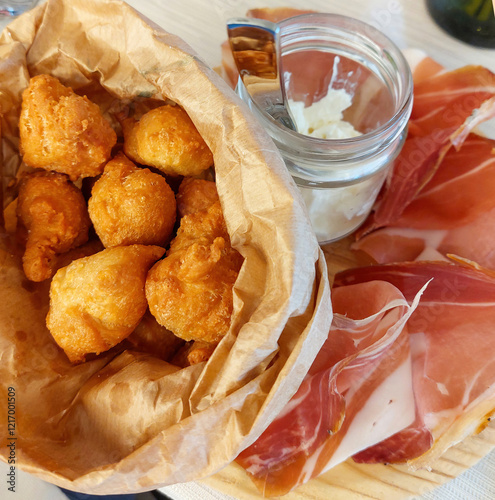 Crispy fried dumplings served with speck ham and stracchinocheese photo