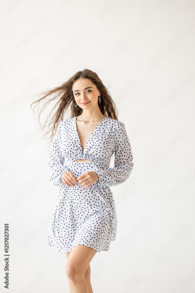 Naklejka premium beautiful woman model posing in white polka dot dress in studio