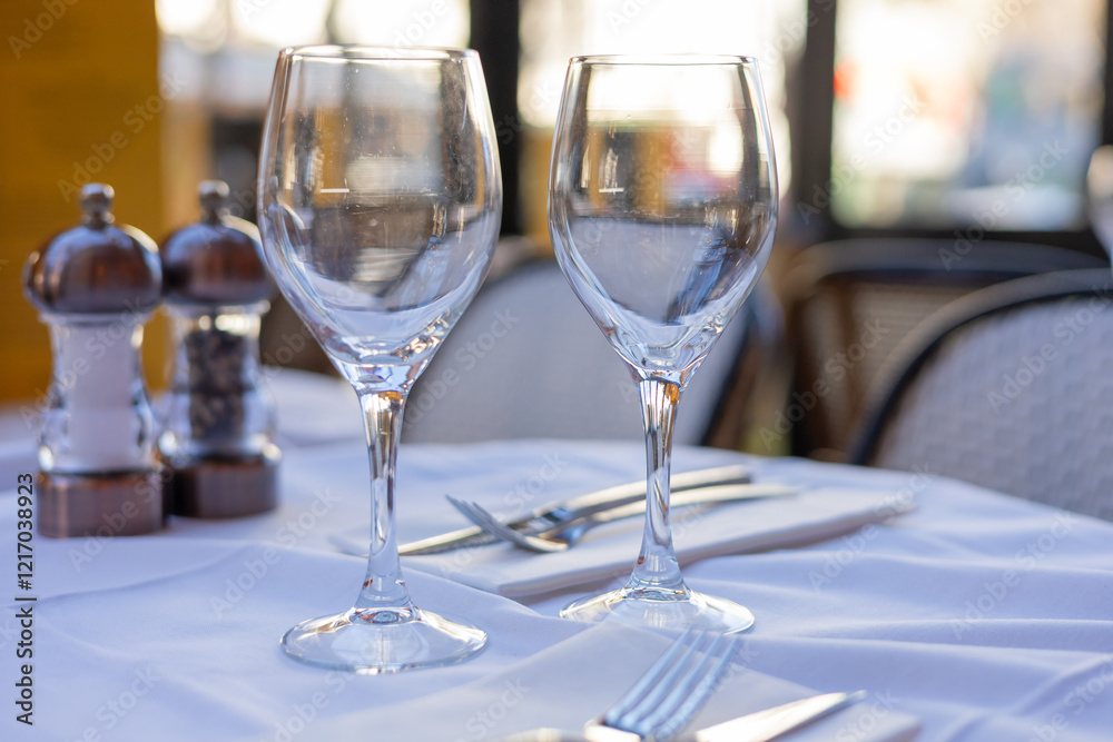 Elegant table setting for fine dining with wine glasses and cutlery in bright restaurant atmosphere Elegant table setting for fine dining with wine glasses and cutlery in bright restaurant atmosphere