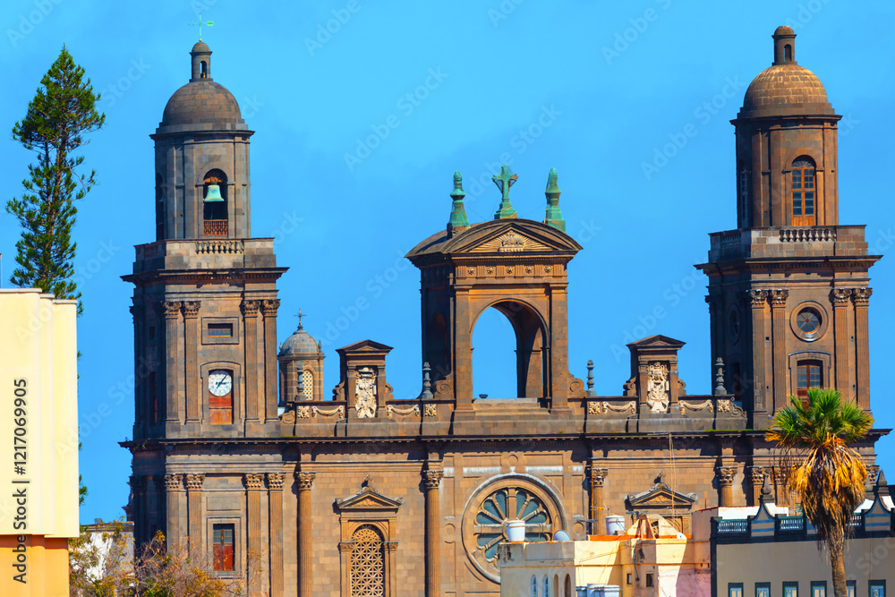 Cathedral of Las Palmas de Gran Canaria. Cathedral of Santa Ana. Grand historic cathedral with two bell towers, intricate stonework, and a large circular window, all set against a clear blue sky