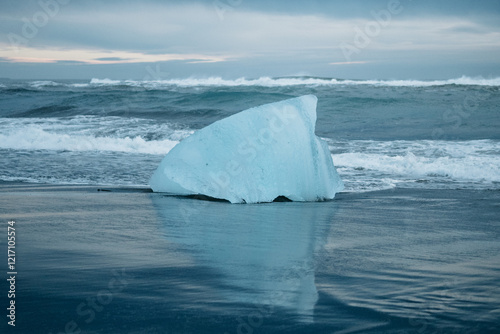 Large blue ice chunk on the black sand of Diamond Beach, South Iceland, at sunrise... photo