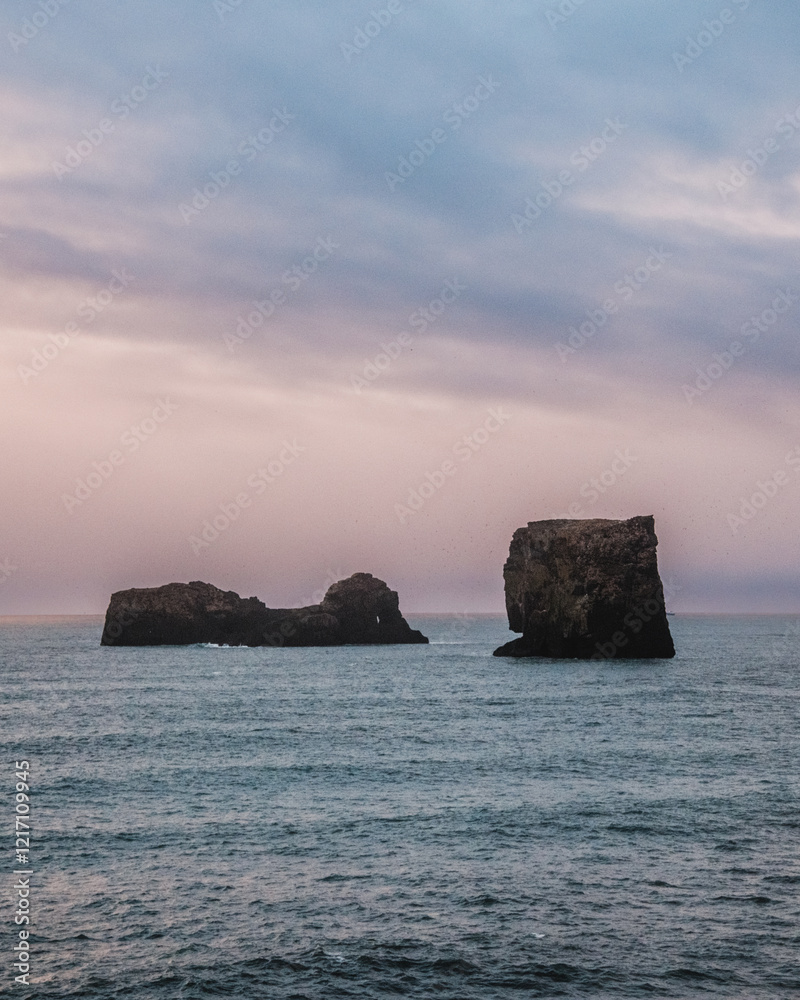 Dramatic seascape with rock formations at Dyrhólaey, South Iceland, under a bright sky Dramatic seascape with rock formations at Dyrhólaey, South Iceland, under a bright sky