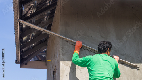 Plastering the cement wall of an outdoor house building with workers working on a construction site