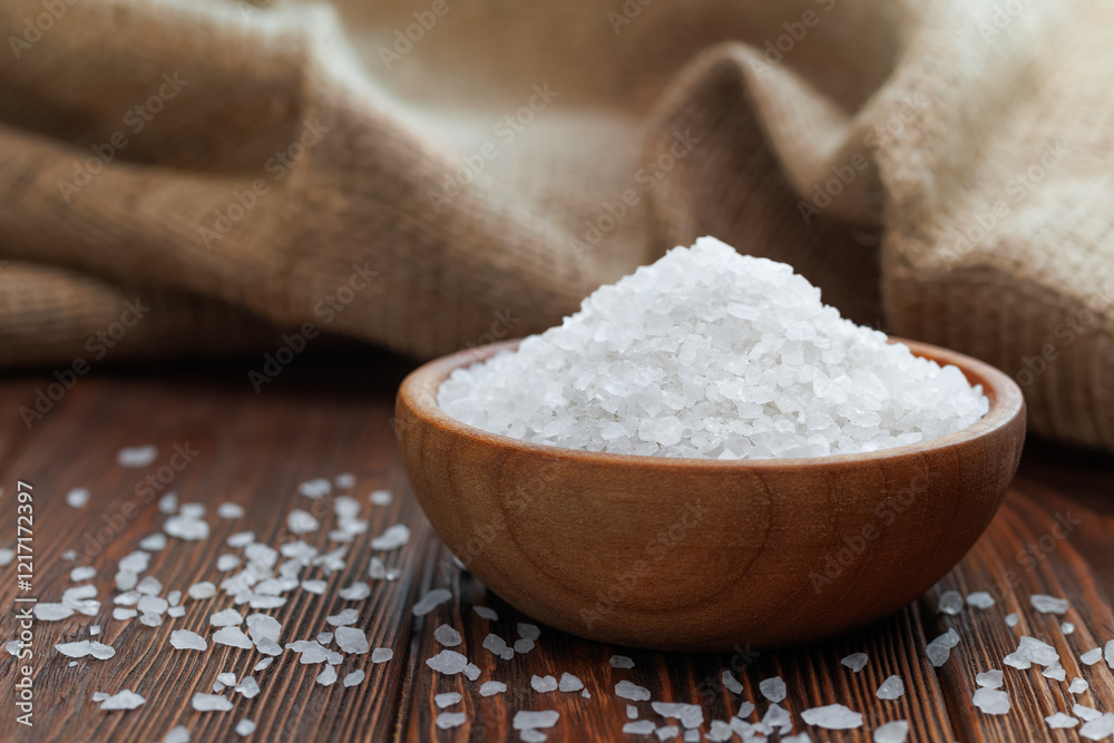 sea salt in wooden bowl on table with burlap on the background sea salt in wooden bowl on table with burlap on the background