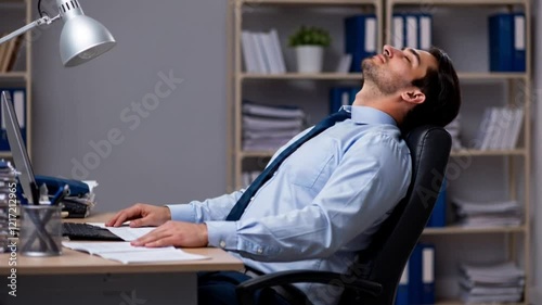 Exhausted office worker sleeps leaning back on his chair after a long day