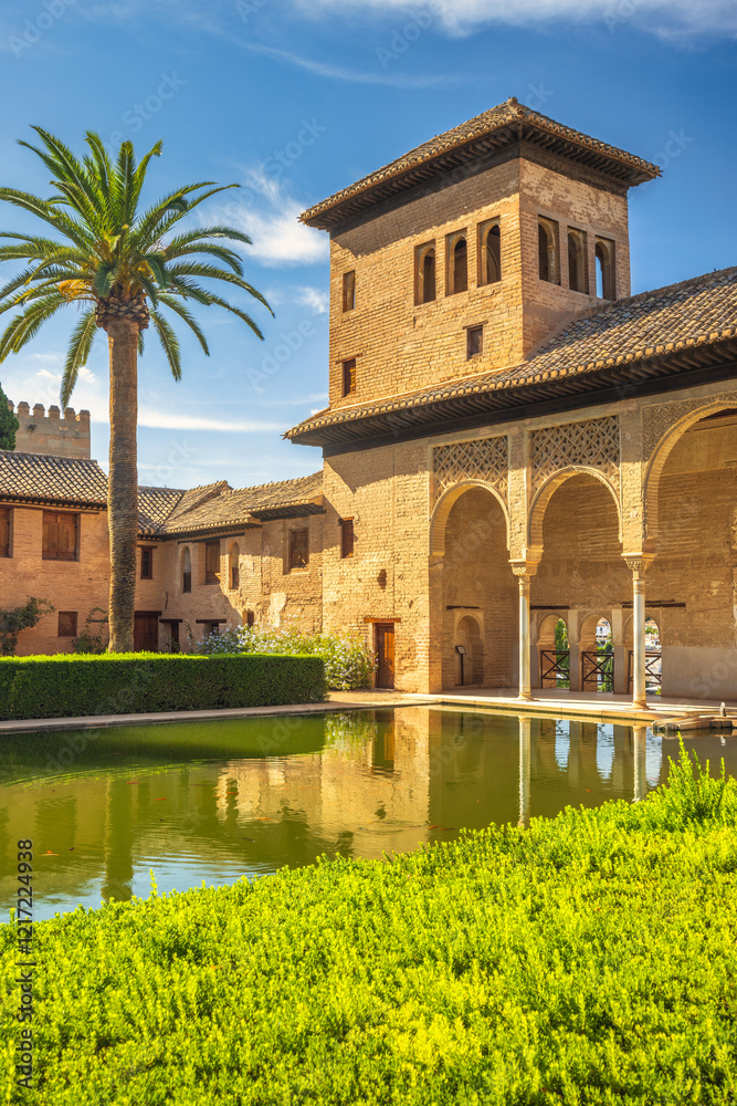 Obraz premium The Partal Palace in the Alhambra complex, Granada, Andalusia, Spain. Serene courtyard with reflecting pool, traditional architecture, and lush greenery.