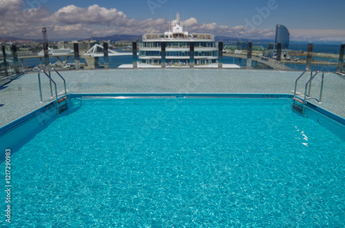 Outdoor infinity swimming pool onboard modern luxury cruiseship cruise ship liner with turquoise water under summer cloud sky photo