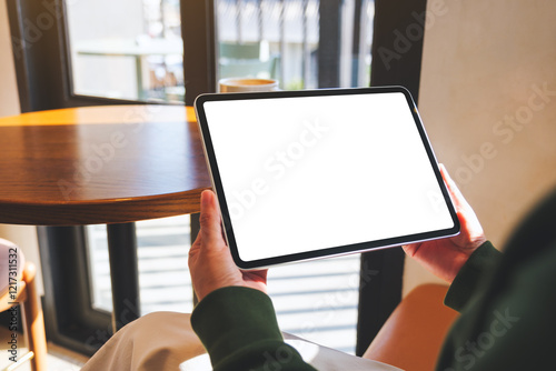 Mockup image of a woman holding digital tablet with blank desktop screen in cafe