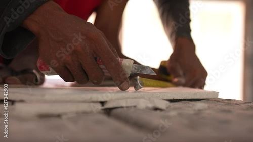 The builder cut by knife in construction. In the office make repaire during hot and suny day in Asia. The man works at construction in showroom photo