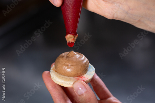 Piping chocolate frosting onto a cookie to create a delicious dessert