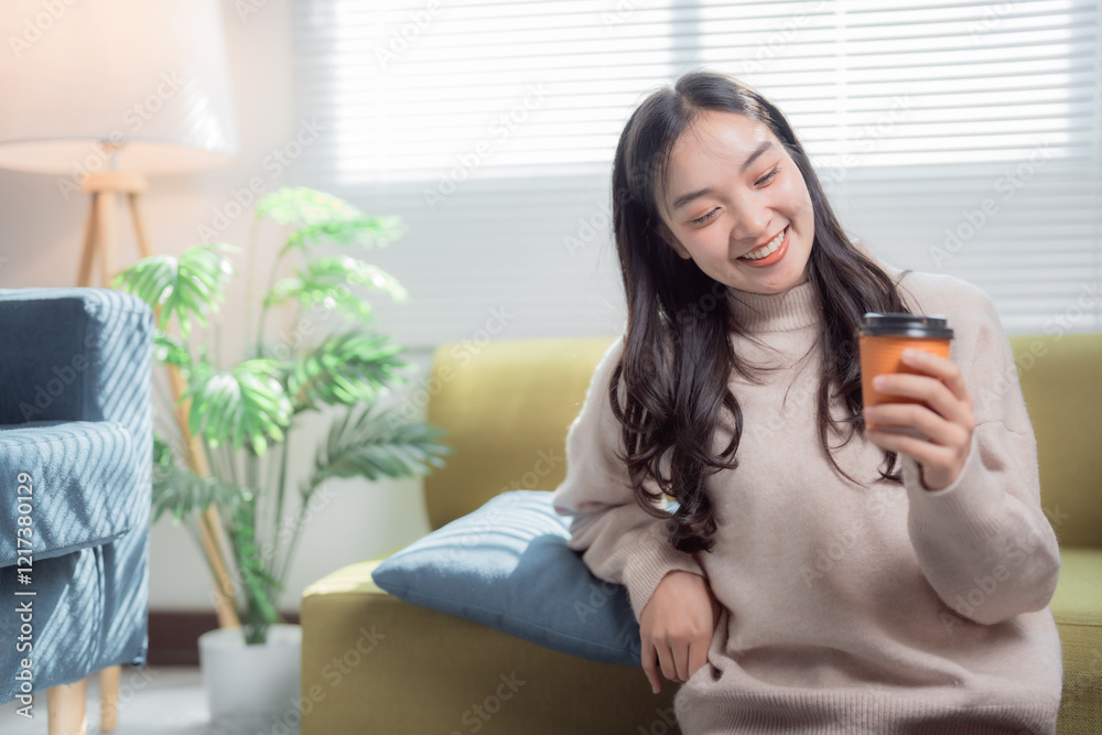 Young asian woman sitting on the floor, wearing a beige sweater, smiling and holding a coffee cup in her living room, enjoying a quiet moment of relaxation Young asian woman sitting on the floor, wearing a beige sweater, smiling and holding a coffee cup in her living room, enjoying a quiet moment of relaxation