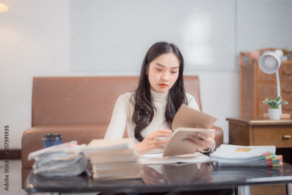Focused Asian female student reading a book and studying at home, surrounded by a variety of textbooks and documents on the table, embodying the essence of education and learning Focused Asian female student reading a book and studying at home, surrounded by a variety of textbooks and documents on the table, embodying the essence of education and learning