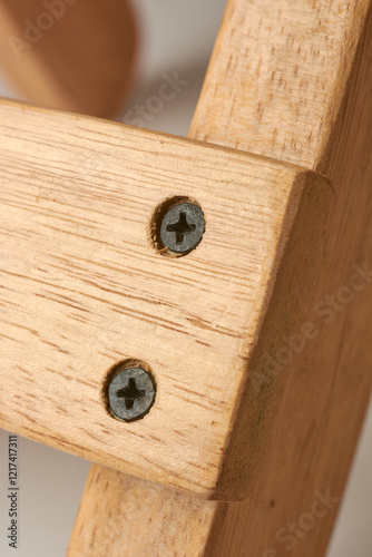 close-up macro view of countersunk black phillips head metal screws driven into the wood to flush with or below the surface, woodworking concept
