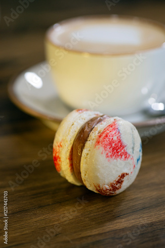 Colorful macaron beside a warm cup of coffee on a wooden table during a relaxed afternoon