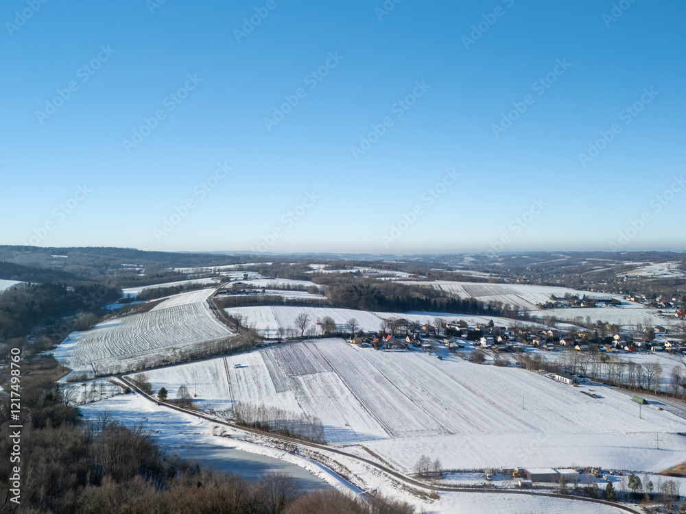 Aerial view of a snowy landscape with fields and a small village under a clear blue sky, showcasing winter beauty and tranquility. Aerial view of a snowy landscape with fields and a small village under a clear blue sky, showcasing winter beauty and tranquility.