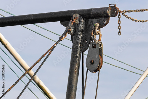 Schilderij op canvas Rusty Old Pulley and Steel Cable Bolted to Black Tubular Metal Frame on Fishing