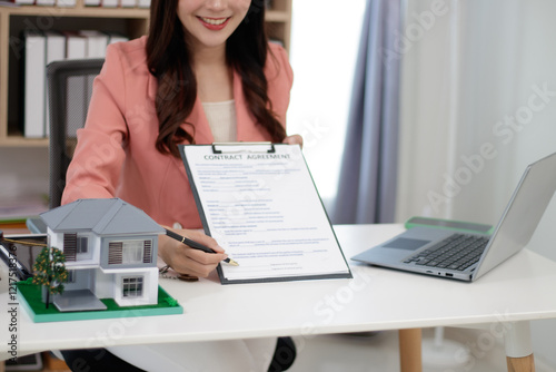 Asian businesswoman looks at Baan Diem, promises to name the house and uses a calculator to calculate the house value. photo