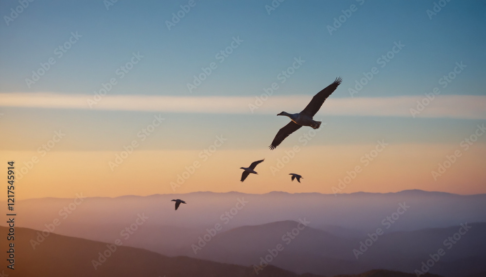 Naklejka premium Silhouetted birds with serene mood, flying over hazy mountains at sunset