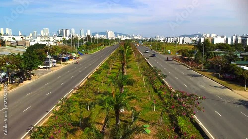 Suburban highway.

A double freeway with a lawn and trees separating the lanes. The city of Nha Trang in Vietnam is visible in the distance. Aerial photography by drone.