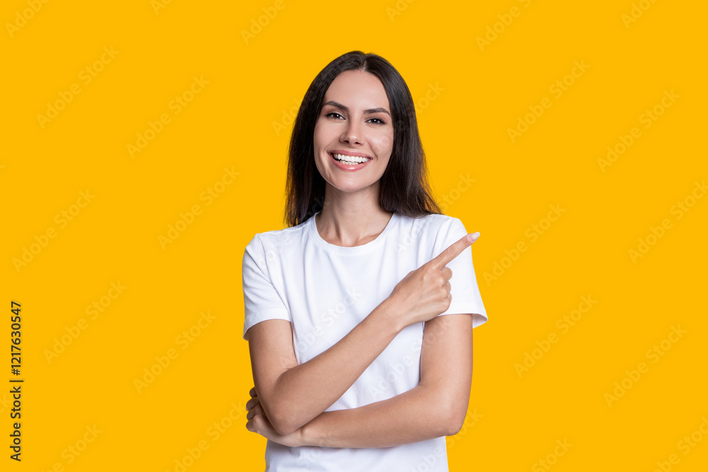 Portrait of millennial girl. Millennial girl presenting product. Woman in white tshirt isolated on yellow. Excited young woman point finger. Stylish female. Advertisement offer. Exclusive offer