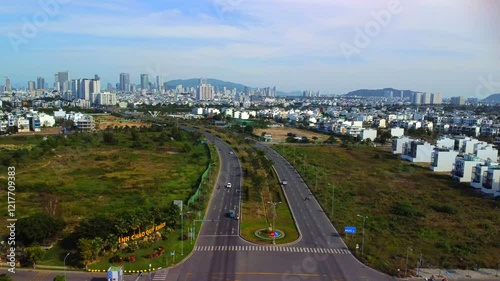 Suburban highway.

A double freeway with a lawn and trees separating the lanes. The city of Nha Trang in Vietnam is visible in the distance. Aerial photography by drone.