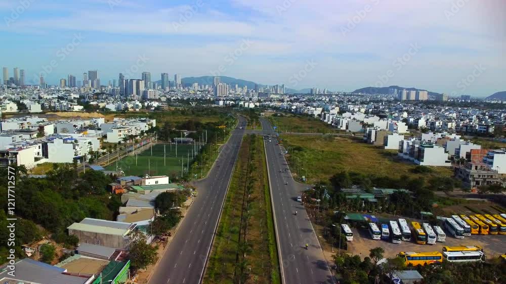 Suburban highway.

A double freeway with a lawn and trees separating the lanes. The city of Nha Trang in Vietnam is visible in the distance. Aerial photography by drone.