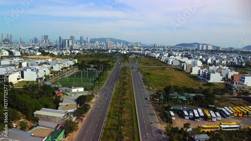 Suburban highway.

A double freeway with a lawn and trees separating the lanes. The city of Nha Trang in Vietnam is visible in the distance. Aerial photography by drone.
