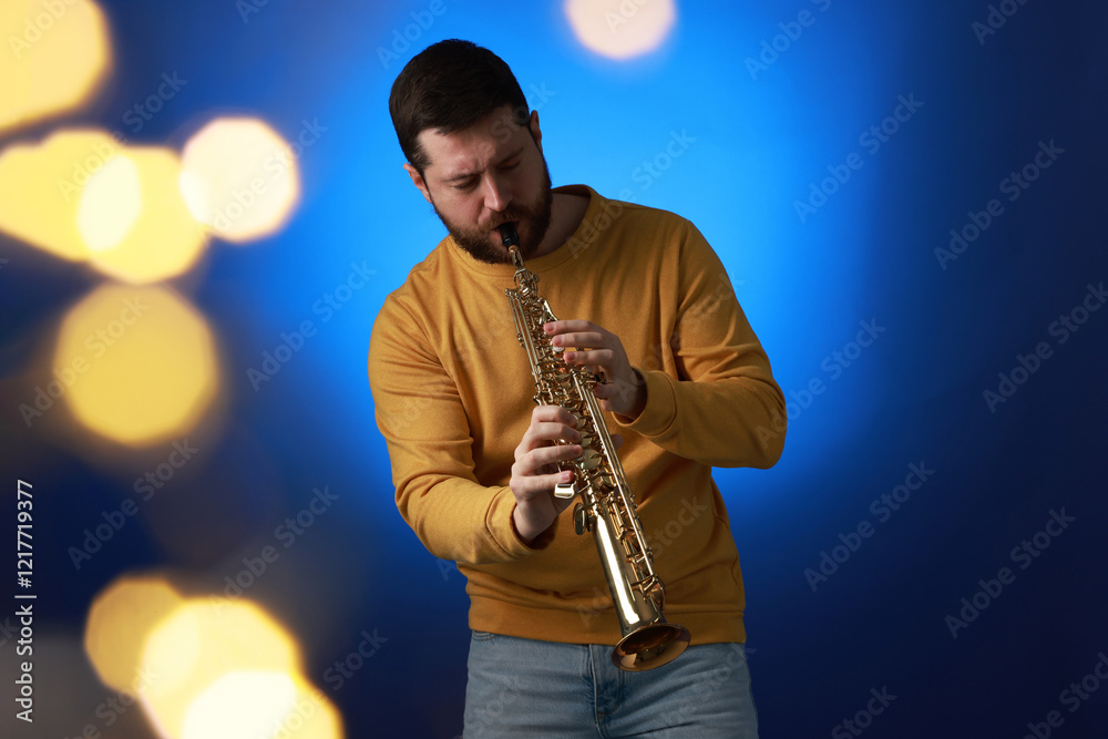 Naklejka premium Professional musician playing soprano saxophone on blue background with blurred lights. Bokeh effect