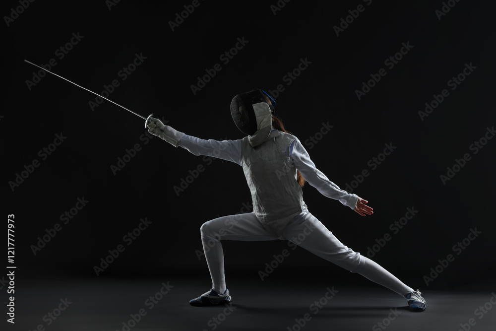 Fencer with epee practicing on dark background Fencer with epee practicing on dark background