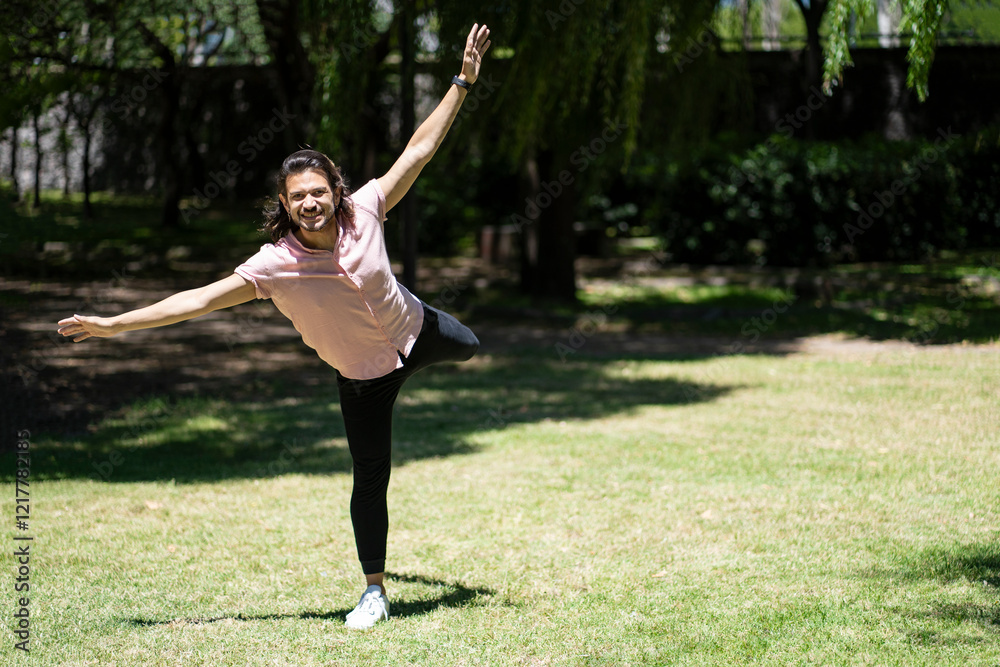 Happy latin man balancing on one leg in a park Happy latin man balancing on one leg in a park