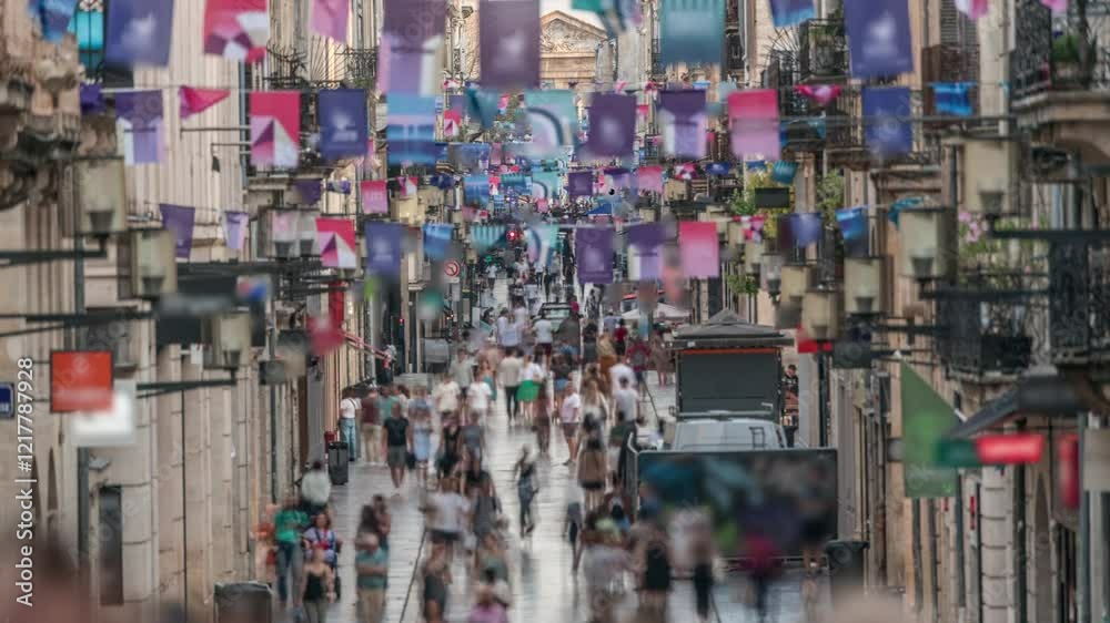 Tourists and locals walking and shopping in Rue Sainte-Catherine timelapse, Bordeaux, France. The longest pedestrian street in the country. Atmosphere of urban life. Colorful flags decorate the street