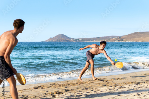 Obraz na płótnie Brothers Enjoying Paddle Ball Game on the Beach w salonie