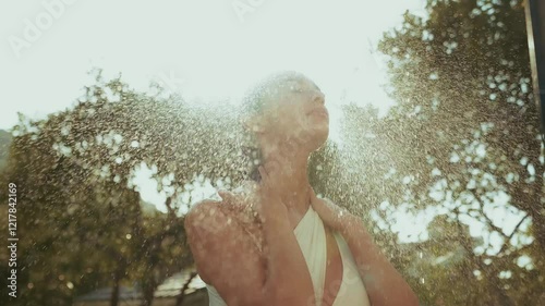 Woman enjoying an outdoor shower in a tropical garden, surrounded by lush greenery and tranquility.