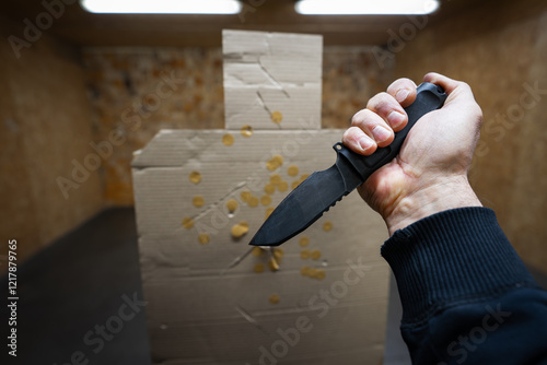 Knife fighting training, first-person view. Knife in a man's hand and a cardboard target in the shape of a body silhouette. photo