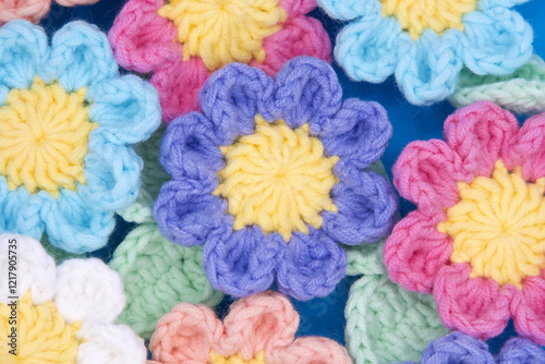 Top view close up of hand crochet spring flowers in pink, purple, ble, peach and white.