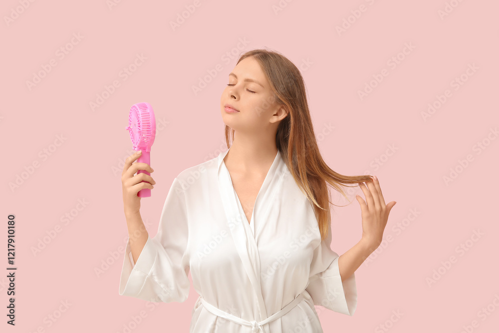 Beautiful young woman with handheld mini fan on pink background Beautiful young woman with handheld mini fan on pink background