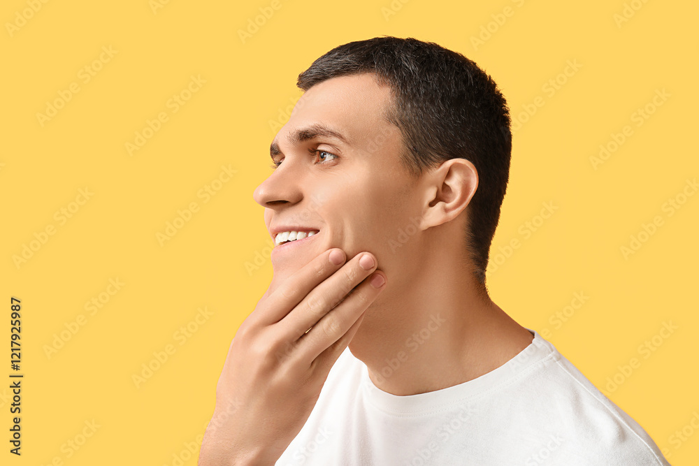 Handsome young man after shaving on yellow background