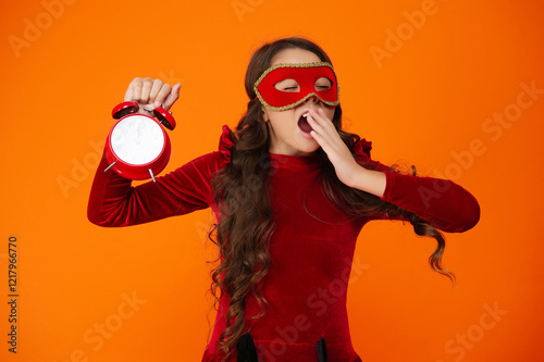 Girl late home after party celebration. End of holiday fun. Countdown. Girl being late and sleepy isolated on orange. Late time. Party countdown. Sleepy teen girl yawning in party mask with clock photo