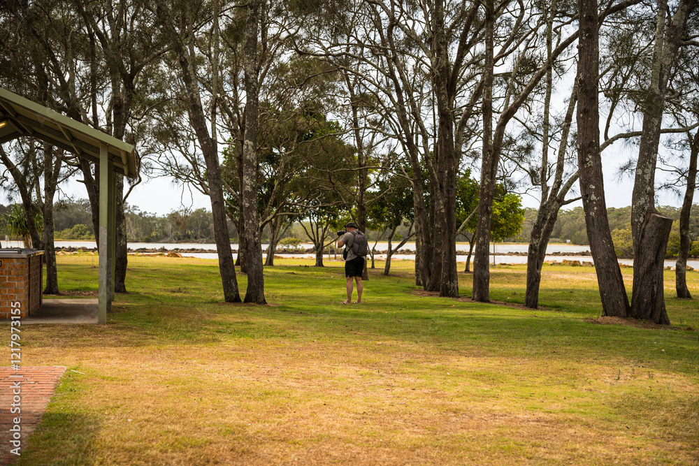 Rear view of a man taking photos in Bellwood Park by Nambucca River, Nambucca Heads, NSW, Australia