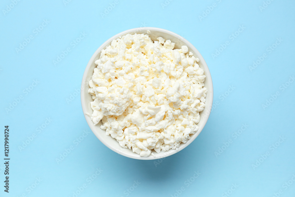 Fototapeta premium Bowl with fresh cottage cheese on blue background