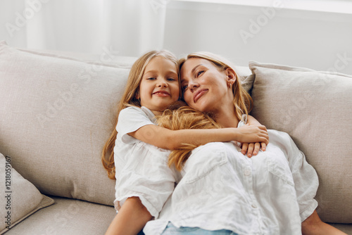 Mother and daughter sharing a tender moment, relaxing on a cozy couch embracing each other affectionately