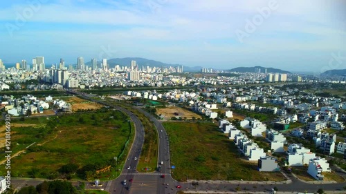 Suburban highway.

A double freeway with a lawn and trees separating the lanes. The city of Nha Trang in Vietnam is visible in the distance. Aerial photography by drone.
