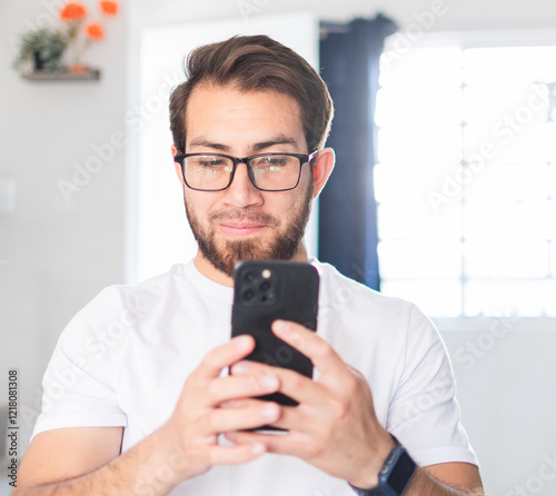 Joven de buen rostro escribiendo en su teléfono celular. 