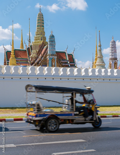 Photography A colorful tuk-tuk navigates the busy streets of Bangkok, speeding by the splendid structures of the Grand Palace